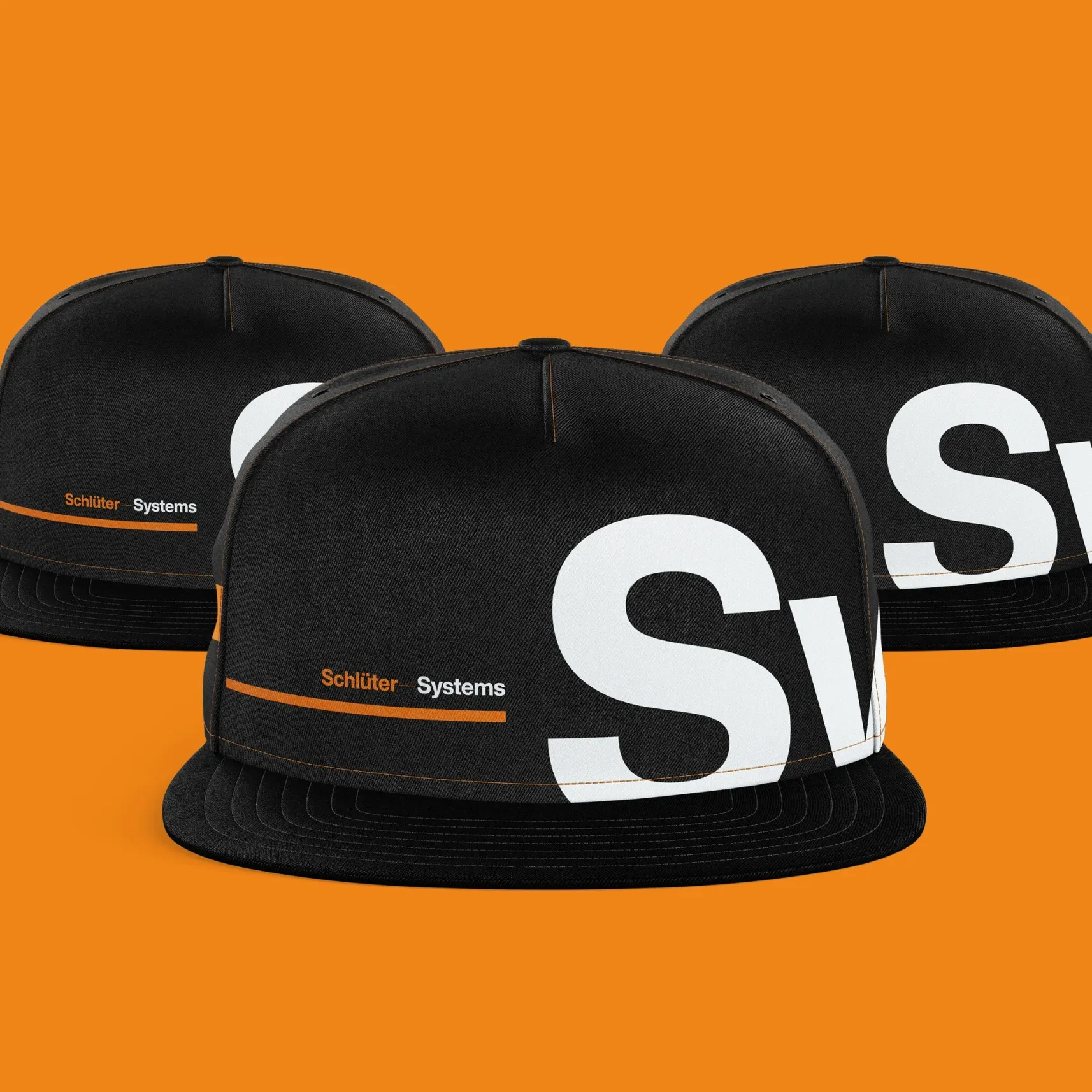 Drei schwarze Caps mit großem weißem S und Schlüter Systems Logo vor orangefarbenem Hintergrund