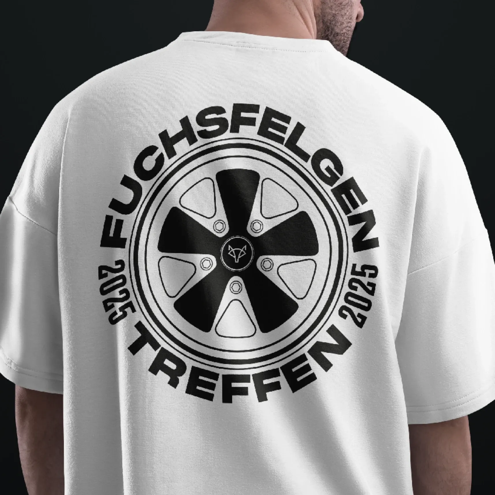 Rückenansicht eines weißen T‑Shirts mit großem Felgenmotiv und der Aufschrift „FUCHSFELGEN TREFFEN 2025“