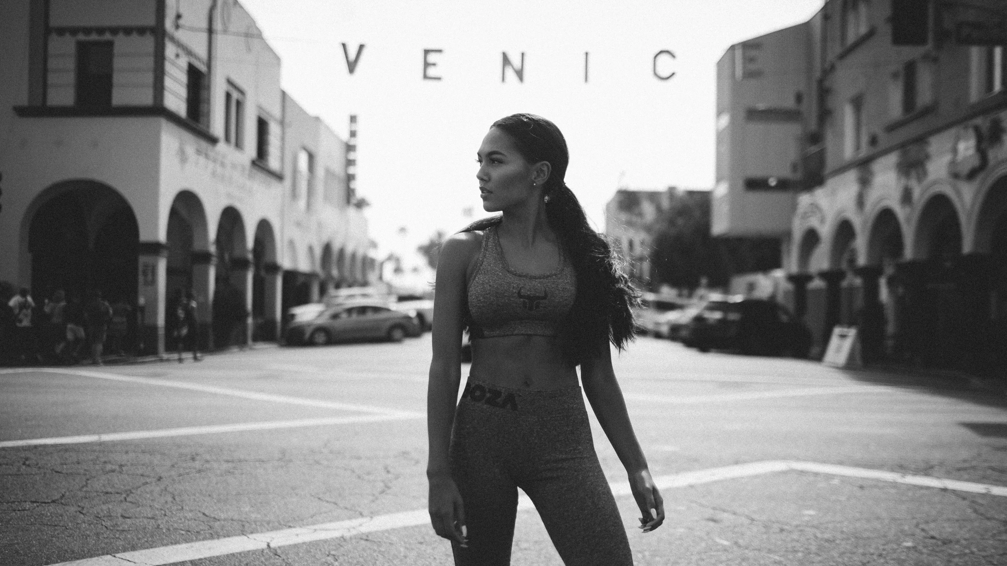 Schwarzweißfoto einer Person in Sportkleidung auf einer Straßenkreuzung mit dem Schriftzug 'VENICE' im Hintergrund