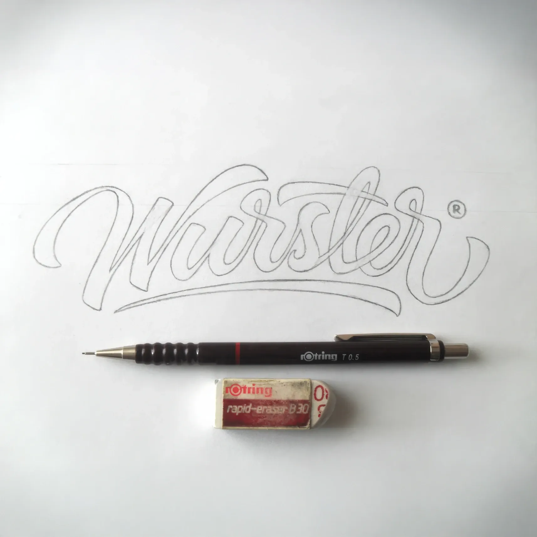 Skizze des Schriftzugs 'Wurster' auf Papier mit rOtring-Druckbleistift und Radiergummi