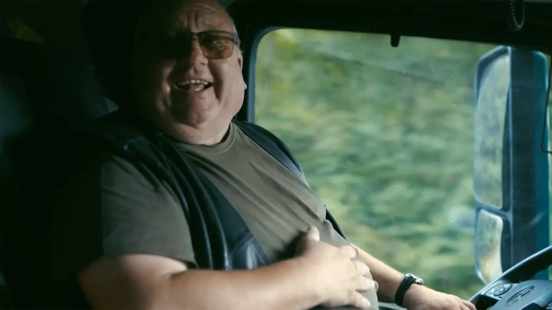 Freundlicher Lkw-Fahrer lächelt in der Fahrerkabine während der Fahrt.