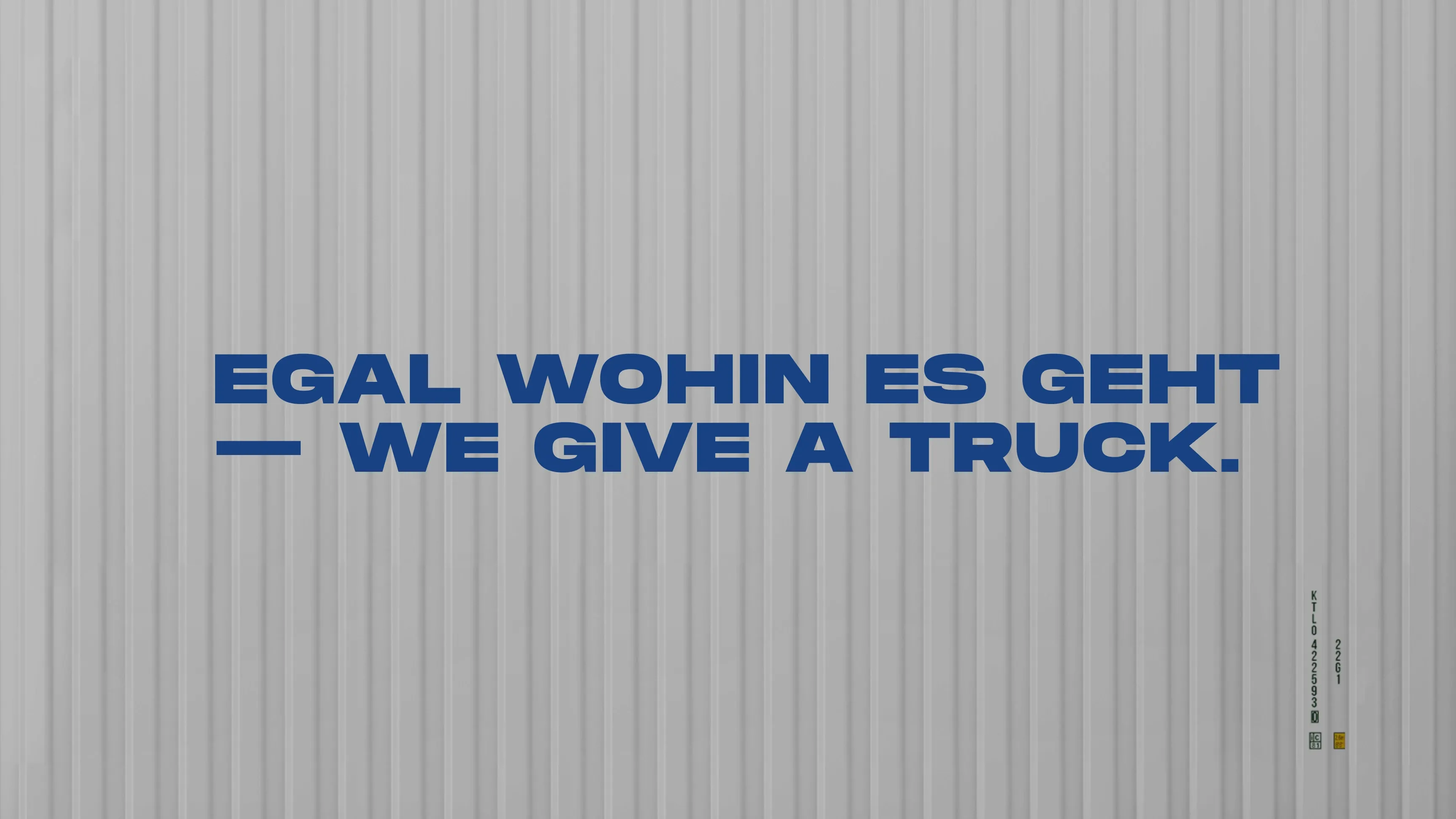 Blauer Schriftzug „EGAL WOHIN ES GEHT — WE GIVE A TRUCK.“ auf grauem, geriffeltem Hintergrund