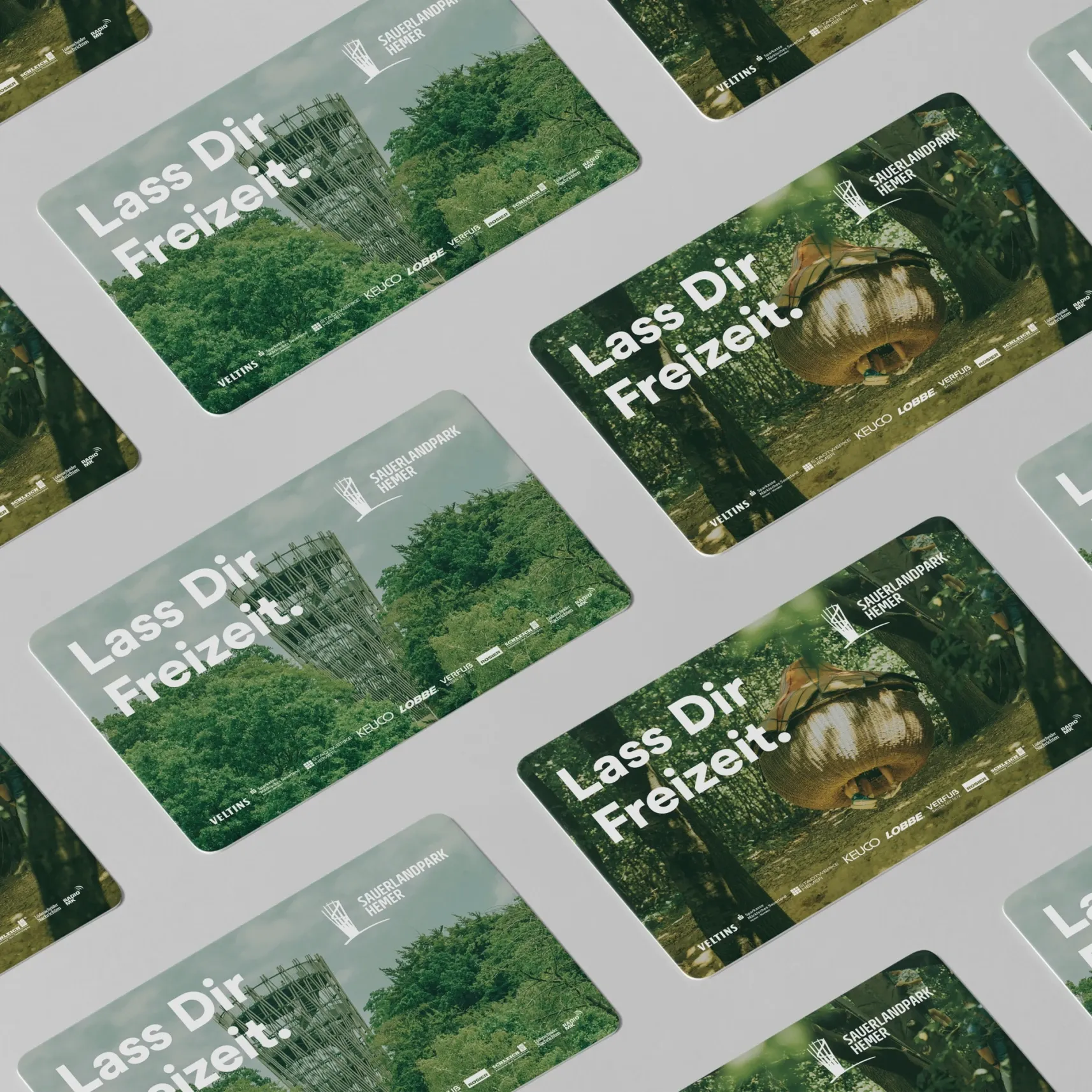 Diagonal angeordnete Karten mit Naturmotiven und dem Schriftzug 'Lass Dir Freizeit' auf grauem Hintergrund