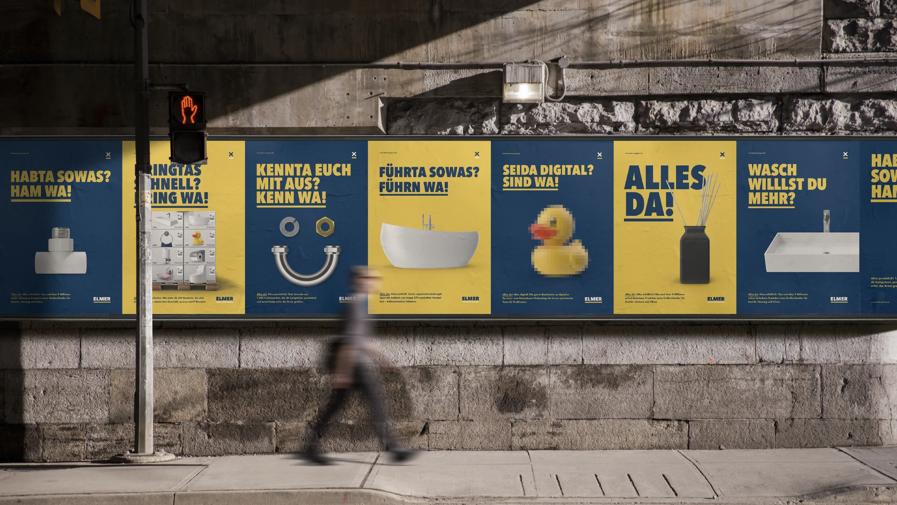 Reihe gelb-blauer Werbeplakate mit Badartikeln an einer Steinwand, verschwommene Person geht auf dem Gehweg vorbei