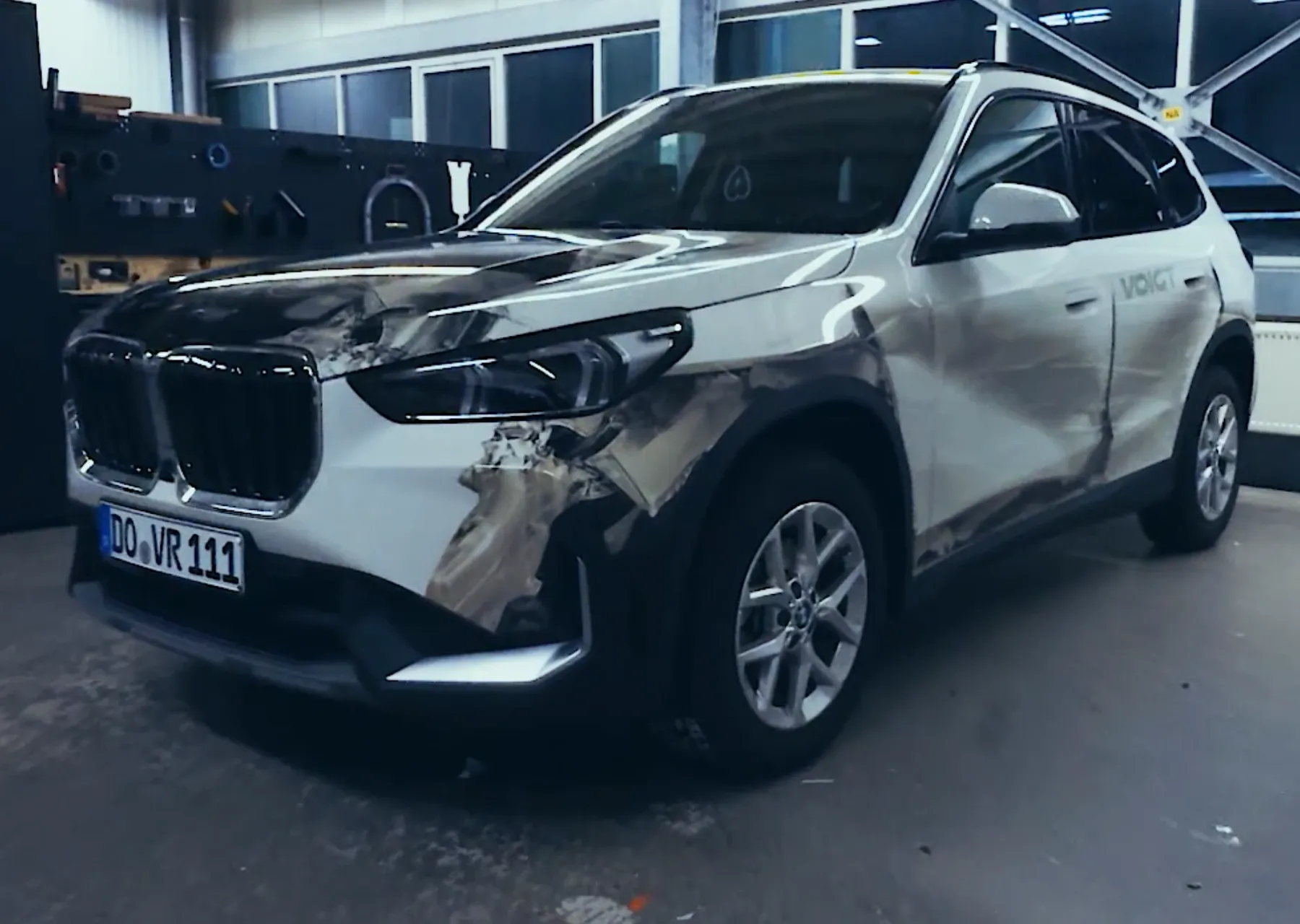 Silberner SUV mit Frontschaden links in einer Werkstatt