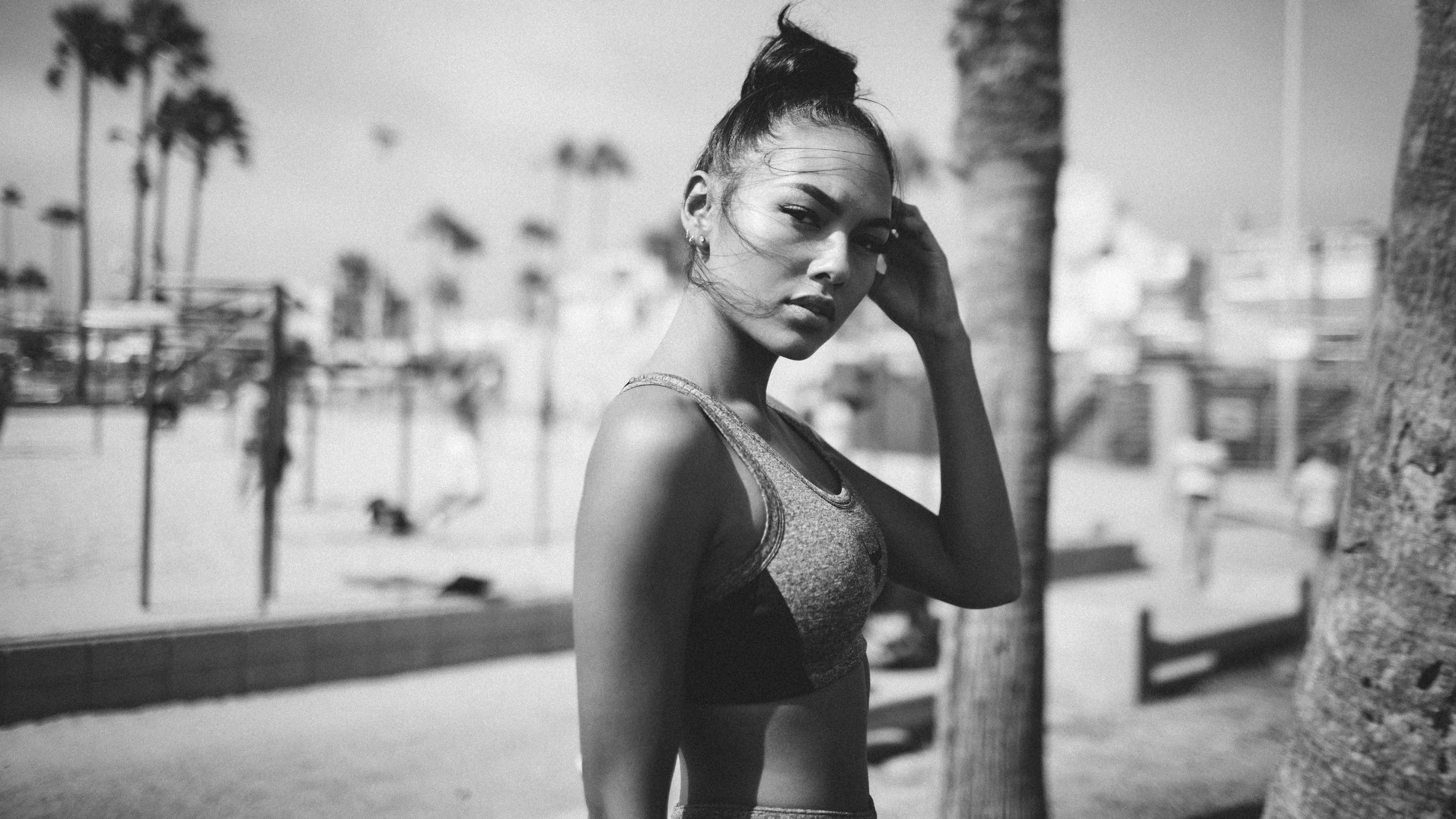 Schwarzweißfoto einer sportlich gekleideten Person im Freien mit Palmen, die in die Kamera blickt