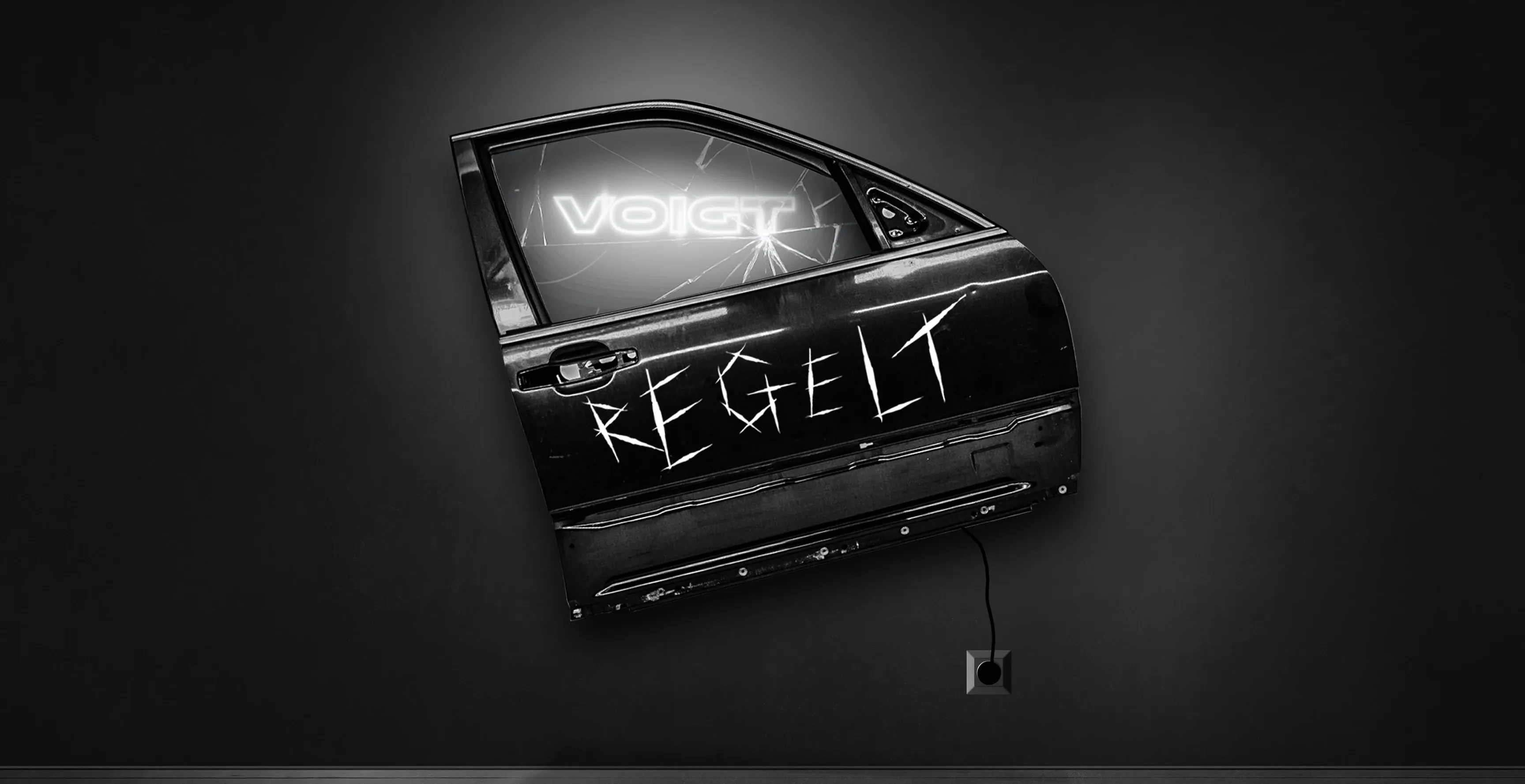 Abmontierte Autotür an dunkler Wand mit der Aufschrift 'REGELT' und Kabel zur Steckdose