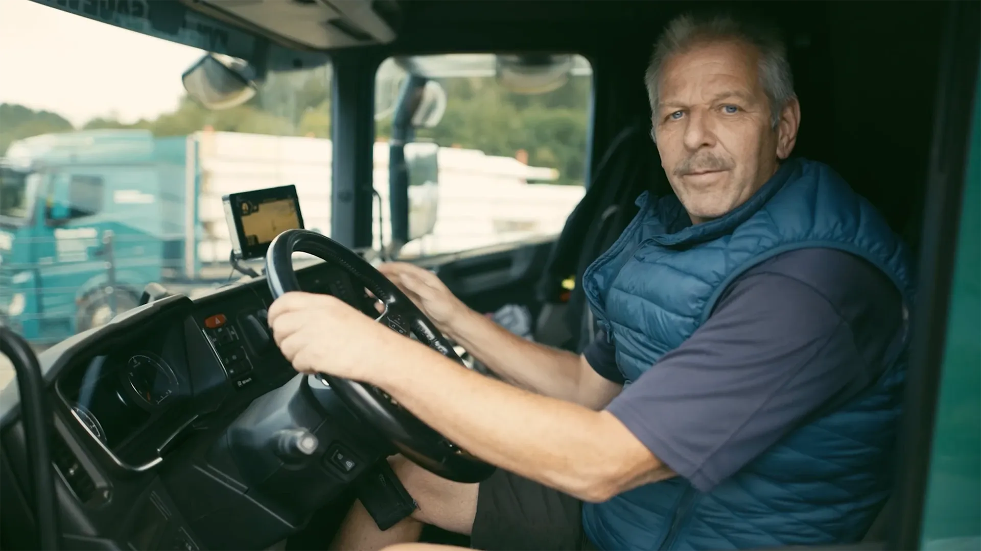 Berufskraftfahrer sitzt in der Lkw-Kabine und bereitet sich auf die Fahrt vor.