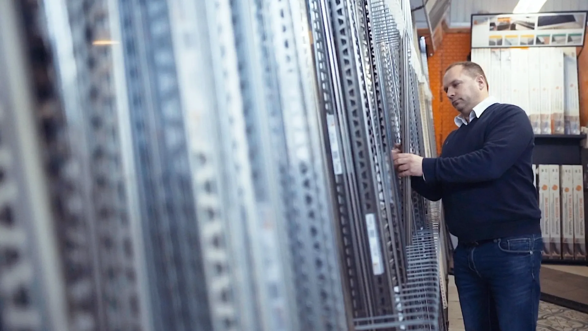 Mann prüft Metallregale in einer Lagerhalle