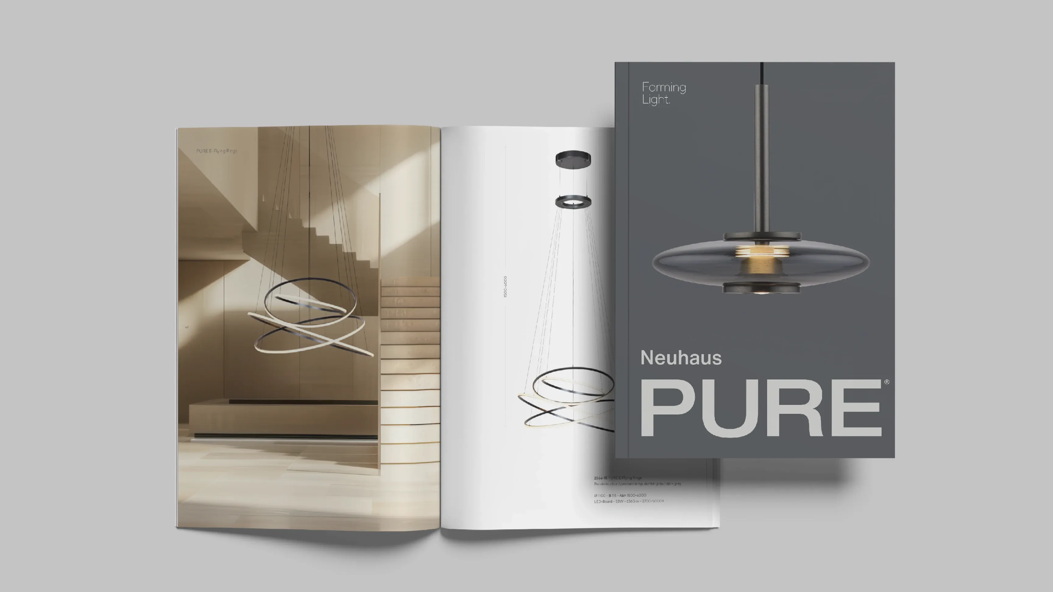 Katalogcover „Neuhaus PURE“ vor einem aufgeschlagenen Magazin mit Fotos und Skizzen einer modernen Pendelleuchte