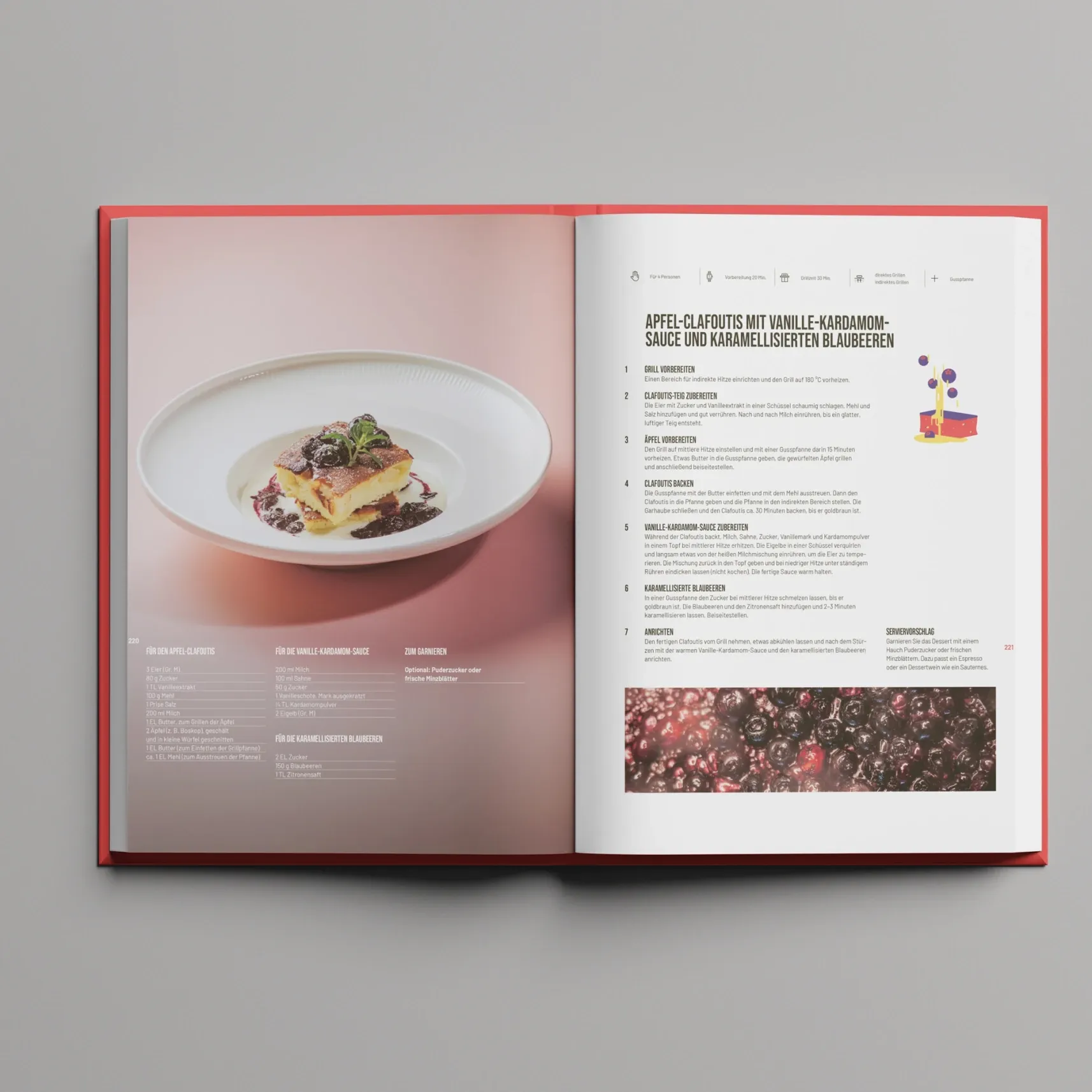 Aufgeschlagenes Kochbuch auf grauem Hintergrund: links ein Dessert auf weißem Teller, rechts ein Rezept für Apfel‑Clafoutis mit Vanille‑Kardamom‑Sauce und karamellisierten Blaubeeren