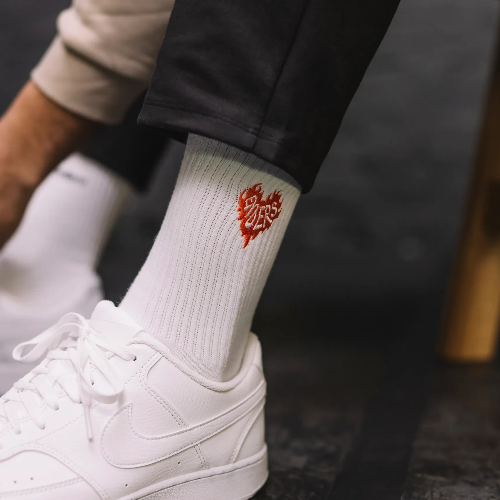 Nahaufnahme eines Fußes mit weißem Sneaker und weißer Socke mit rotem Herzlogo