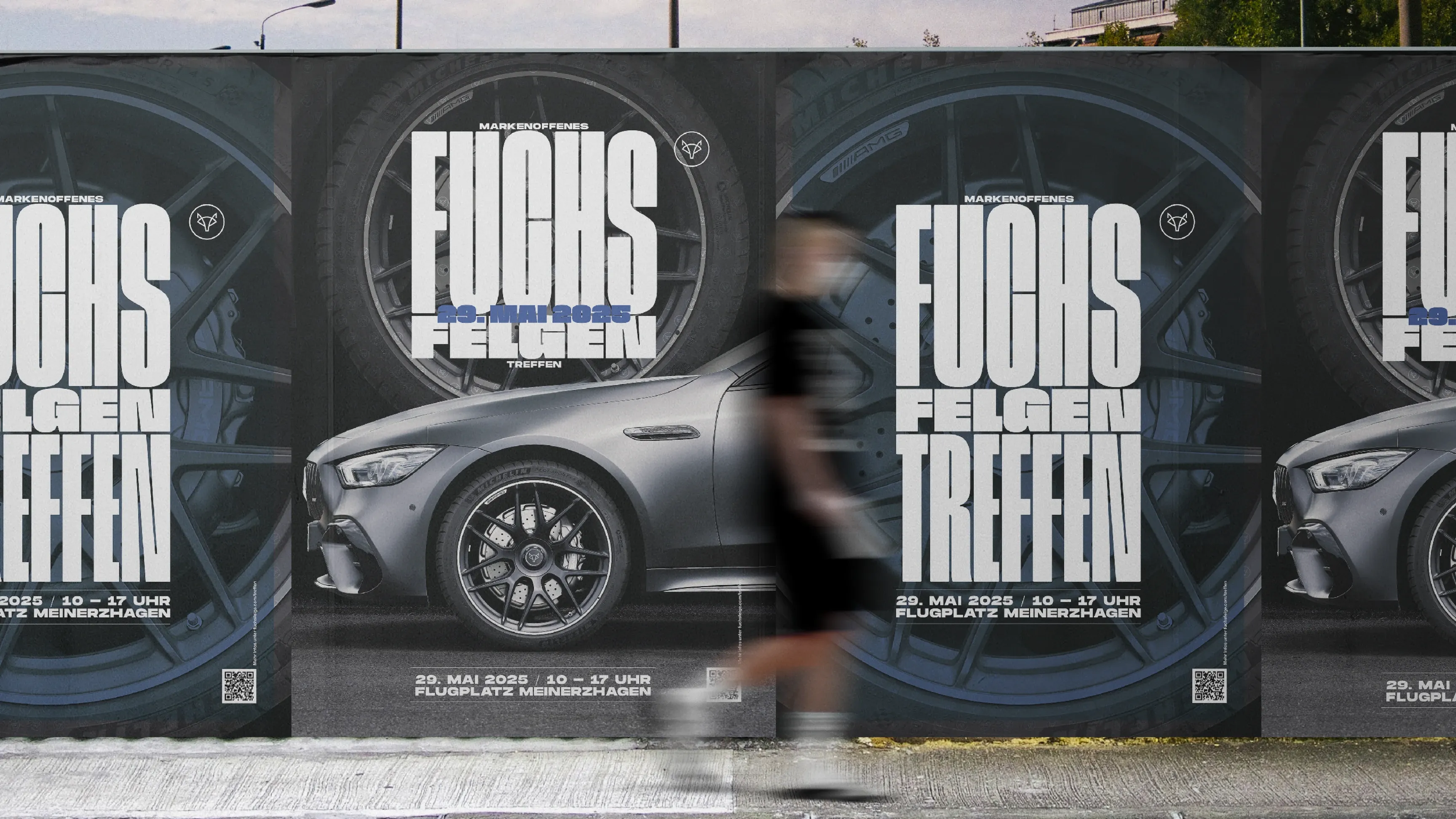 Unscharfer Passant vor Plakatwand mit Werbung „Fuchs Felgen Treffen“ und einem Auto