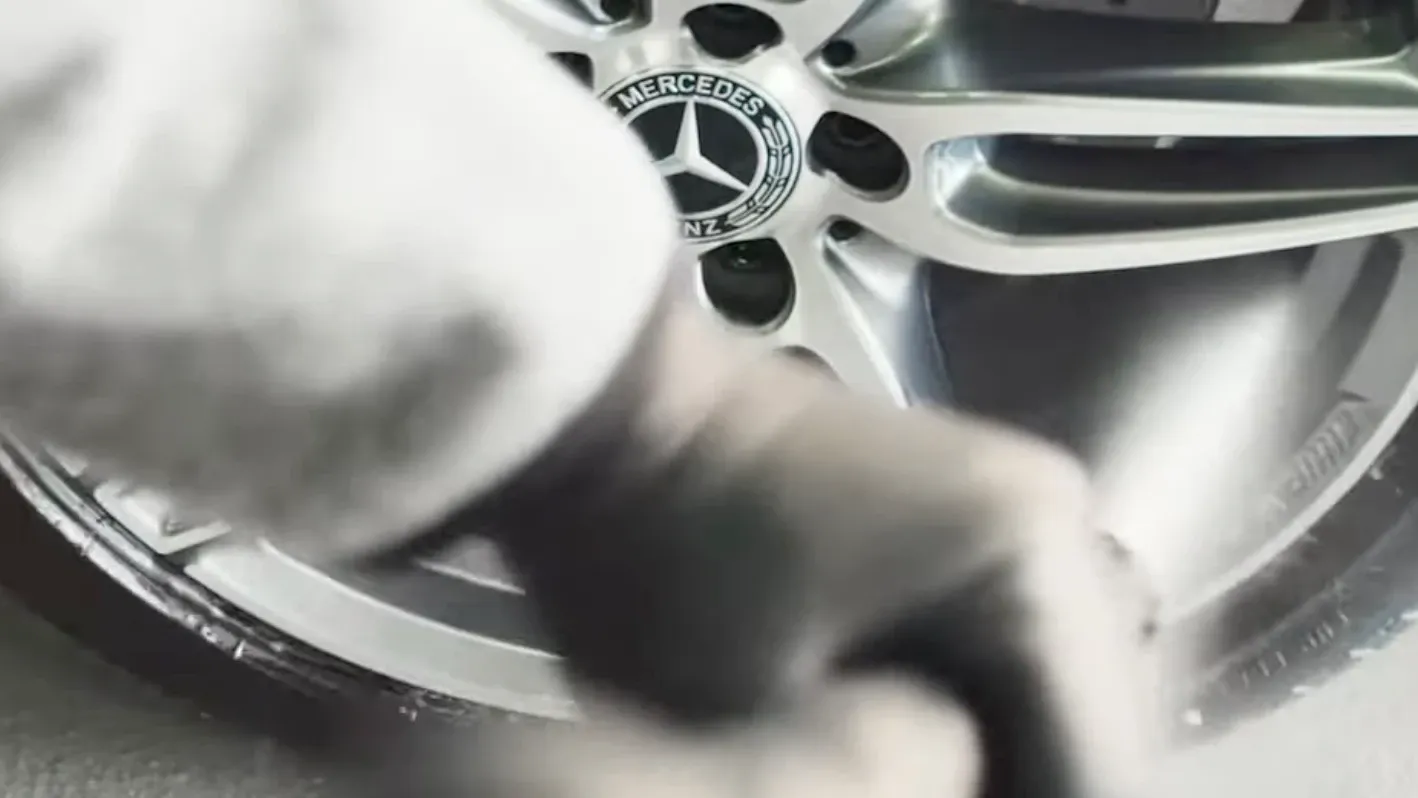 Nahaufnahme einer Mercedes-Benz-Alufelge, die mit Reiniger besprüht wird