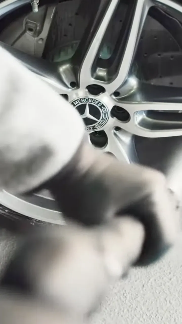 Nahaufnahme einer Mercedes-Benz-Alufelge, die mit Reiniger besprüht wird