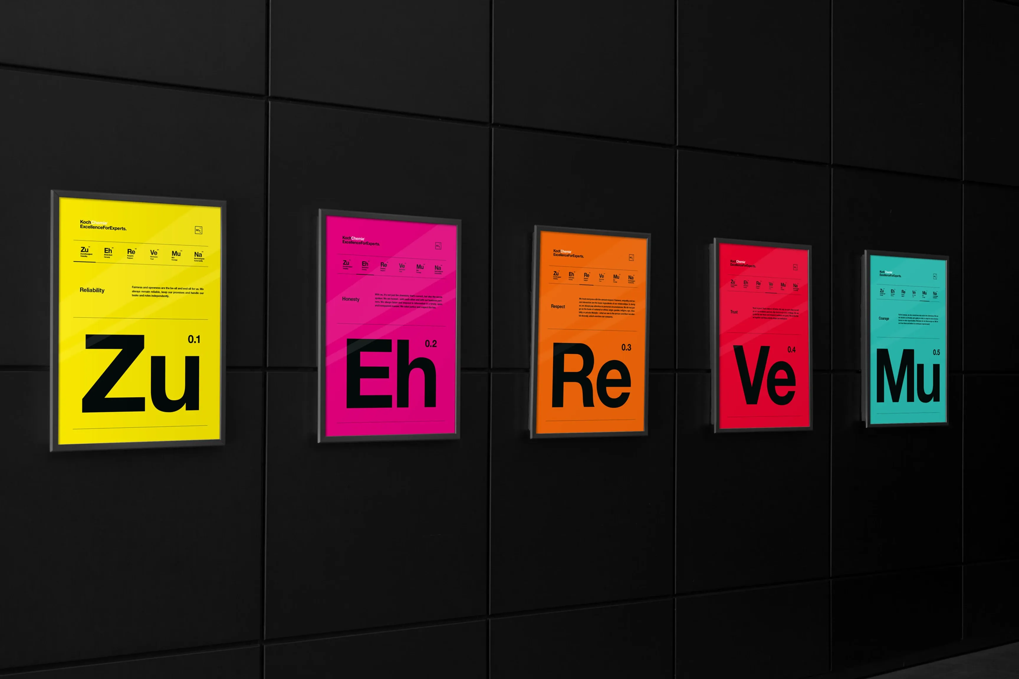 Fünf bunte Plakate mit großen schwarzen Buchstaben an einer dunklen Wand