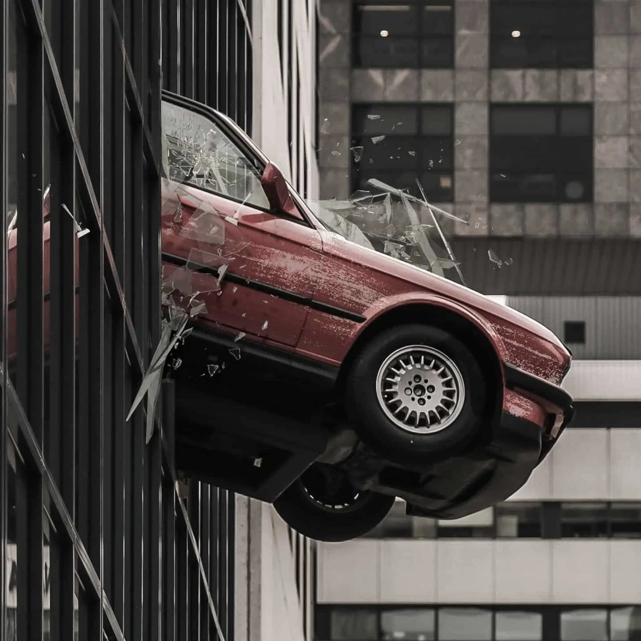 Rotes Auto durchbricht die Glasfassade eines Bürogebäudes