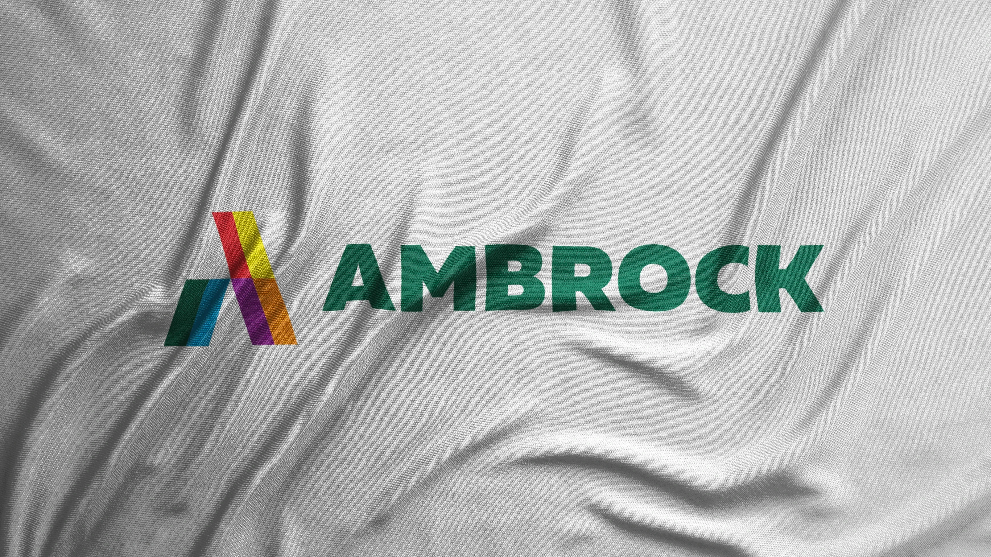 AMBROCK-Logo mit buntem A auf zerknittertem weißen Stoff